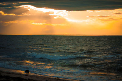 Scenic view of sea against dramatic sky during sunset