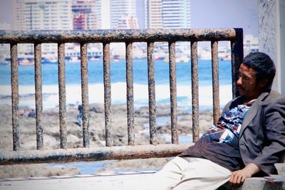 Side view of man sitting on railing during winter