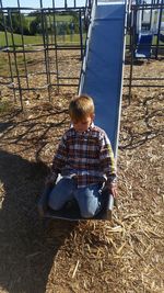 Boy kneeling on slide at playground