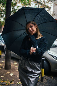 Young woman with umbrella standing in rain