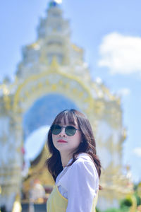 Young woman wearing sunglasses while standing against sky