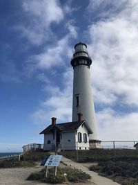 Low angle view of lighthouse by building against sky