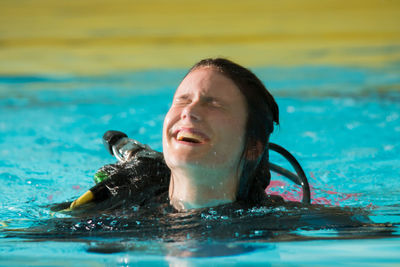 Close-up of cheerful young woman swimming in pool