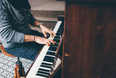 Midsection of man playing piano at home