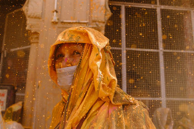 Colorful bokeh with saint lady in mask in yellow outfit