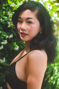 Portrait of asian woman wearing swimsuit in front of a flower bush