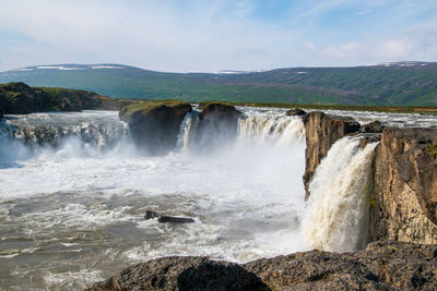 Scenic view of waterfall against sky