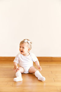 Cute baby girl on hardwood floor at home