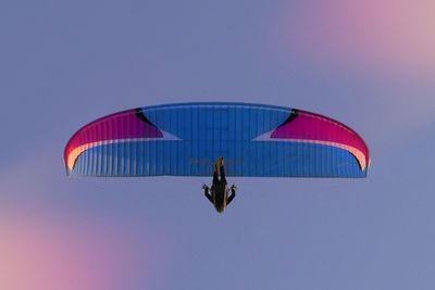 Low angle view of person paragliding against blue sky