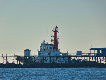 View of factory by sea against clear sky