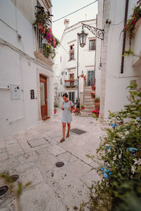 Rear view of man walking on footpath amidst buildings