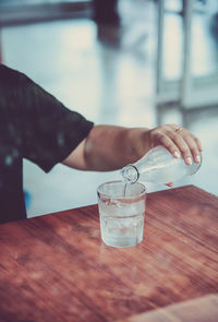 Close-up of hand holding drink on table