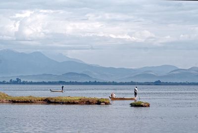 People in boat on lake against sky