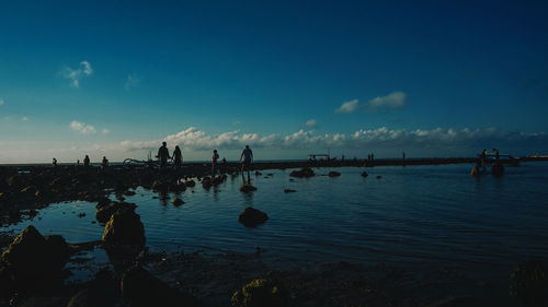 Silhouette people on beach against sky