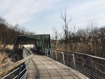 Railing by trees against sky