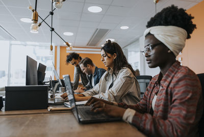 Business colleagues using laptops while working at desk in office