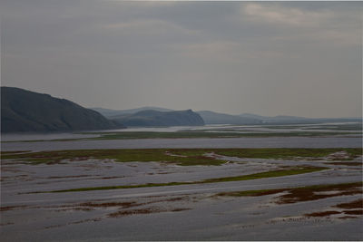 Scenic view of sea and mountains against sky