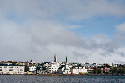 Sea by buildings against sky in city