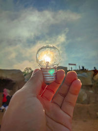 Midsection of person holding crystal ball against sky