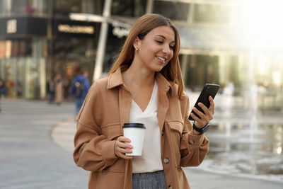 Smiling woman using mobile phone on street