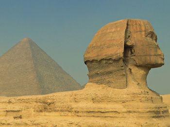 Sphinx and great pyramid against clear sky