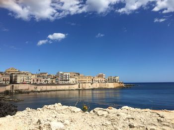 Built structure by sea against blue sky