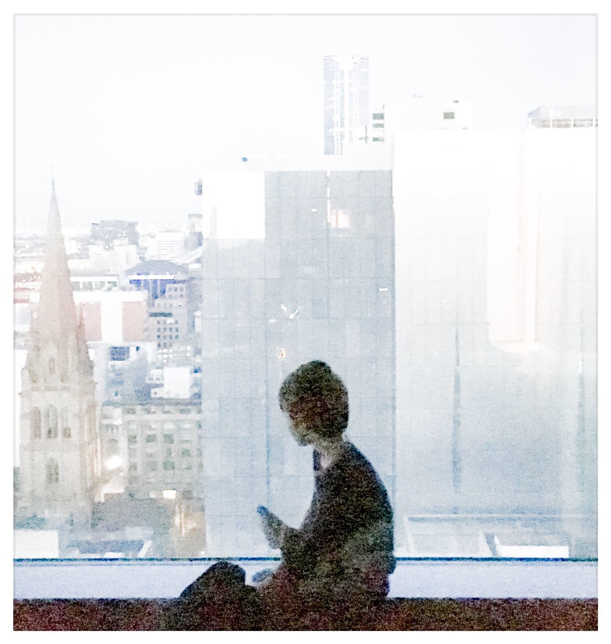 REAR VIEW OF MAN WITH CITYSCAPE AGAINST WINDOW