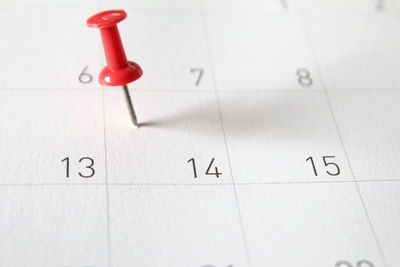 Close-up of red thumbtack on calendar