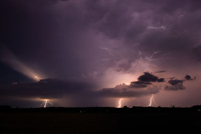 Scenic view of storm clouds over field at night