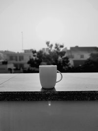 Close-up of coffee cup on table against sky
