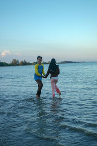 Couple standing in sea against sky