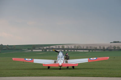 Airplane flying over field against sky