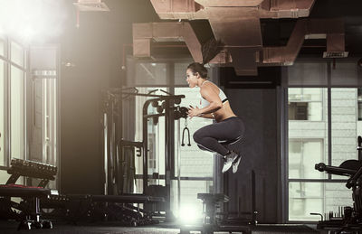 Side view of young woman exercising at gym