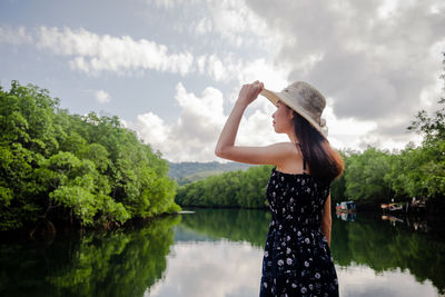 Woman standing by lake against sky