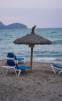 Deck chair on beach against sky