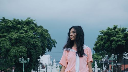 Portrait of young woman standing against clear sky