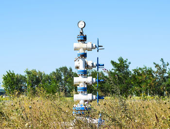 Blue oil pump on grassy field against clear blue sky