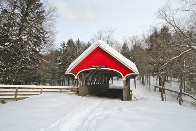 Red covered bridge and snow covered trees against sky. franconia notch, new hampshire 