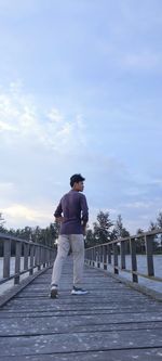 Rear view of man standing on footpath against sky