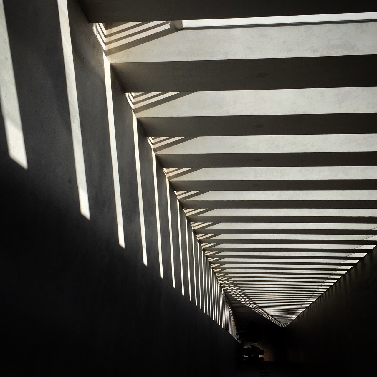 architecture, built structure, in a row, diminishing perspective, transportation, the way forward, railing, low angle view, city, modern, indoors, repetition, building exterior, day, pattern, no people, shadow, striped, sunlight