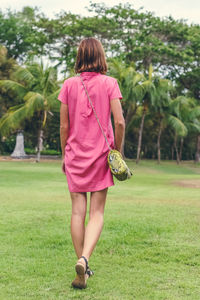 Rear view of woman walking on field