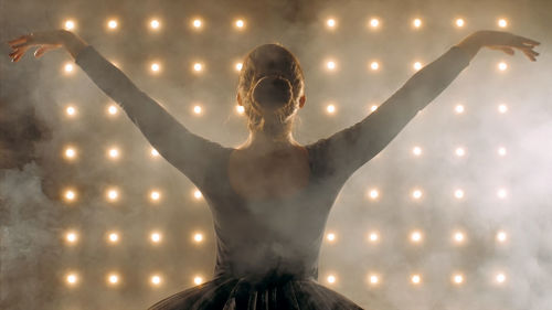 Ballerina dancing against illuminated lights