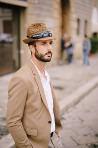 Young man looking away while standing on street