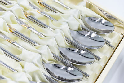 High angle view of spoons with fabric arranged in box on table