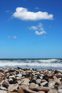 Pebbles on beach against blue sky
