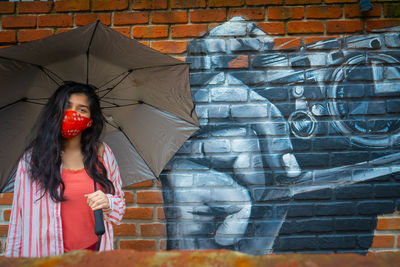 Full length of woman standing against graffiti wall
