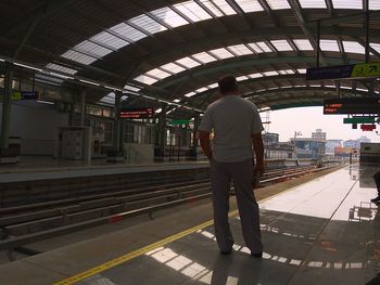 Rear view of man standing on railroad station platform