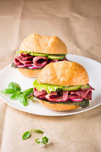 Ready-to-eat hamburgers with pastrami, vegetables and basil on a plate on craft paper