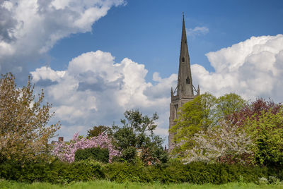 View of trees and building against cloudy sky