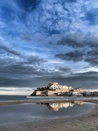 Built structure on beach by sea against sky